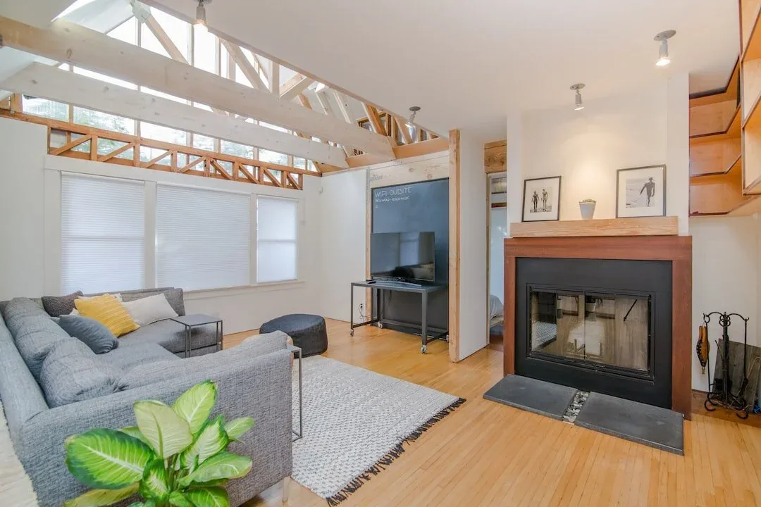 Living room with exposed ceiling trusses and a corner fireplace